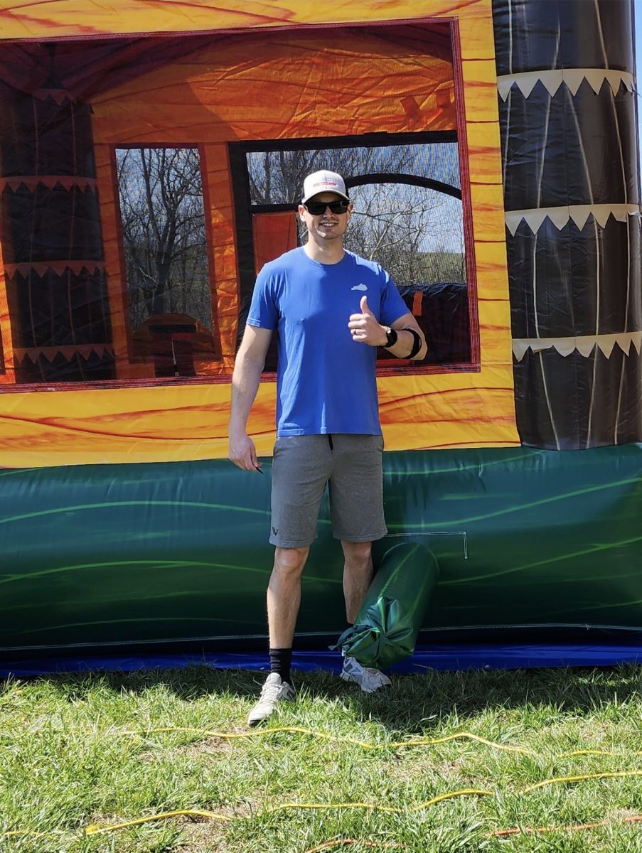 The owner of Backyard Responders, Ricky, standing next to his bounce house rental, and he is giving a thumbs up.