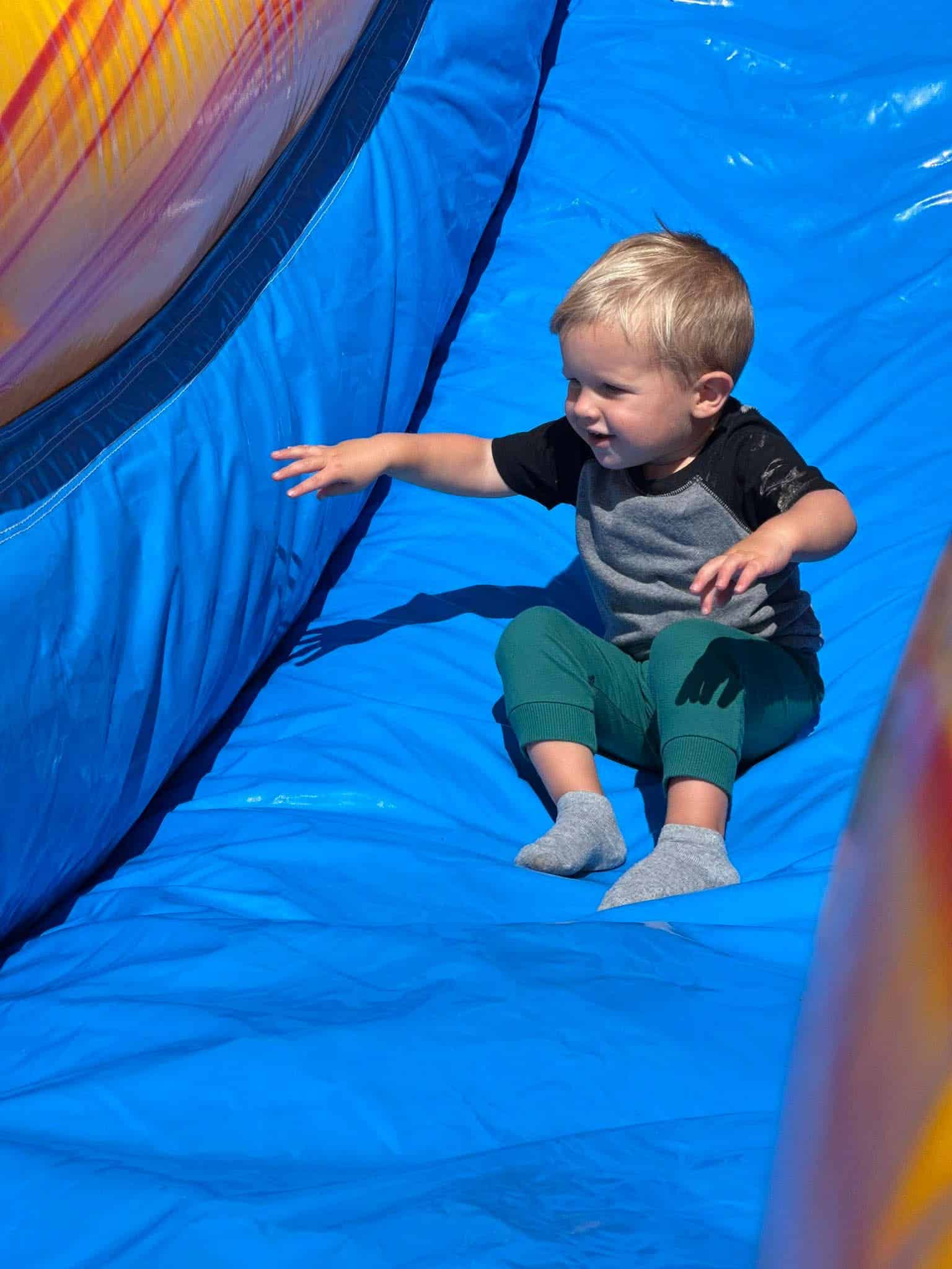 Kids inflatable obstacle course rental in Nicholasville, KY with a child sliding down the inflatable finish slide