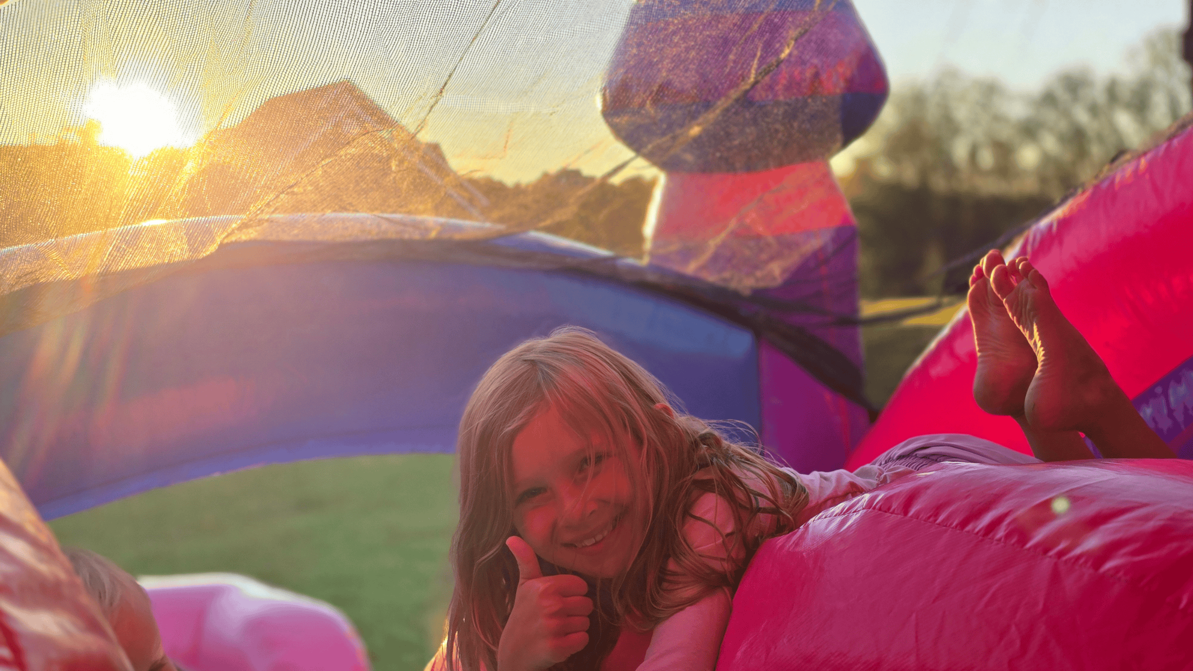 Girl giving thumbs up on a Purplish inflatable bounce house rental from Backyard Responders in Central Kentucky