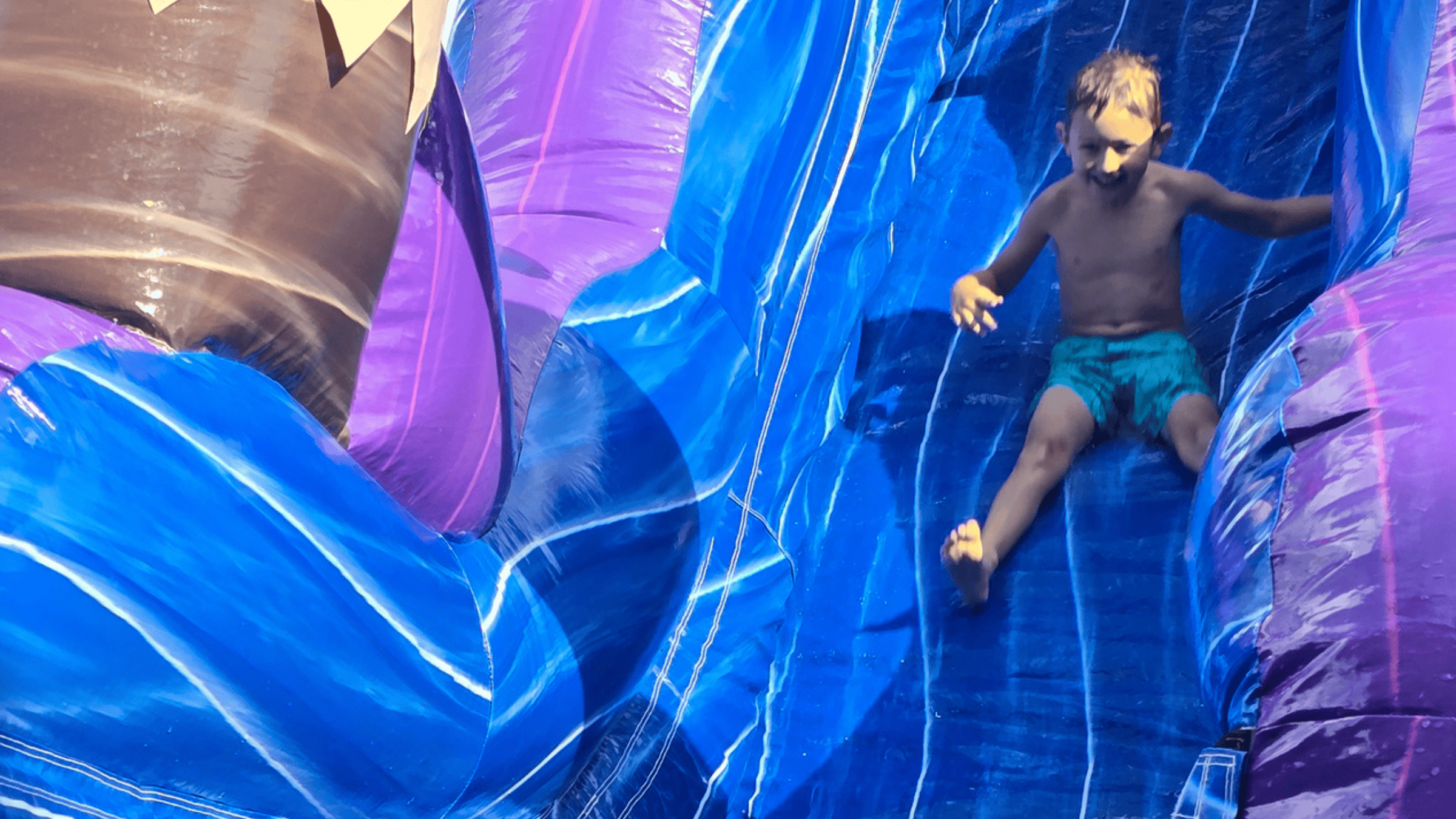 Kid sliding down the Purple Plunge giant water slide rental in Central Kentucky